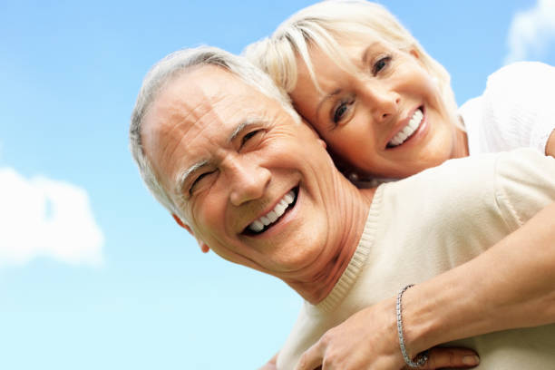 Portrait of a happy senior man piggybacking a mature woman against sky