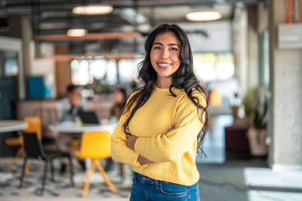 A young adult Hispanic female stands with arms crossed